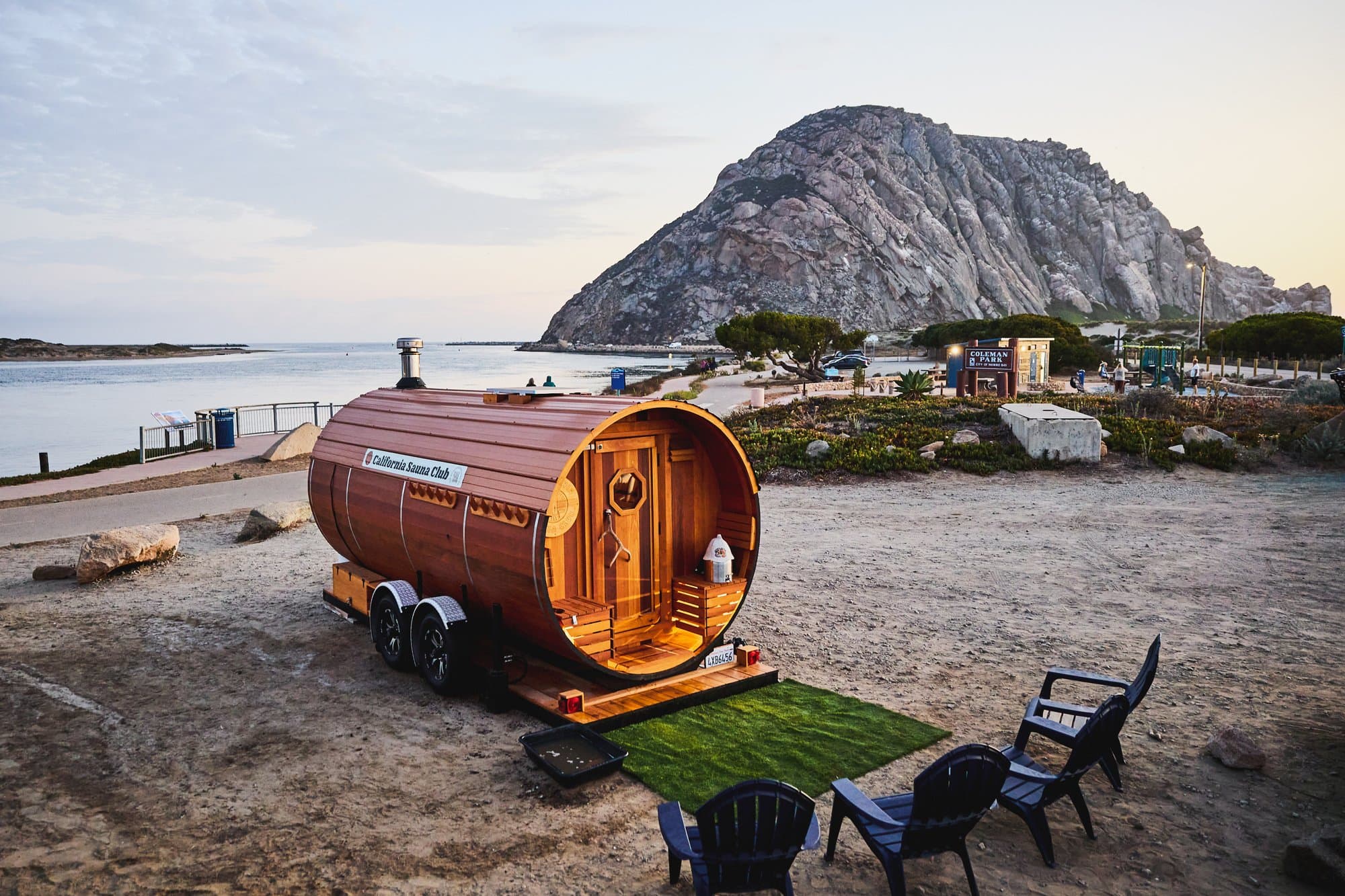 The California Sauna Club barrel sauna at Coleman Park, with Morro Rock and the harbor behind it