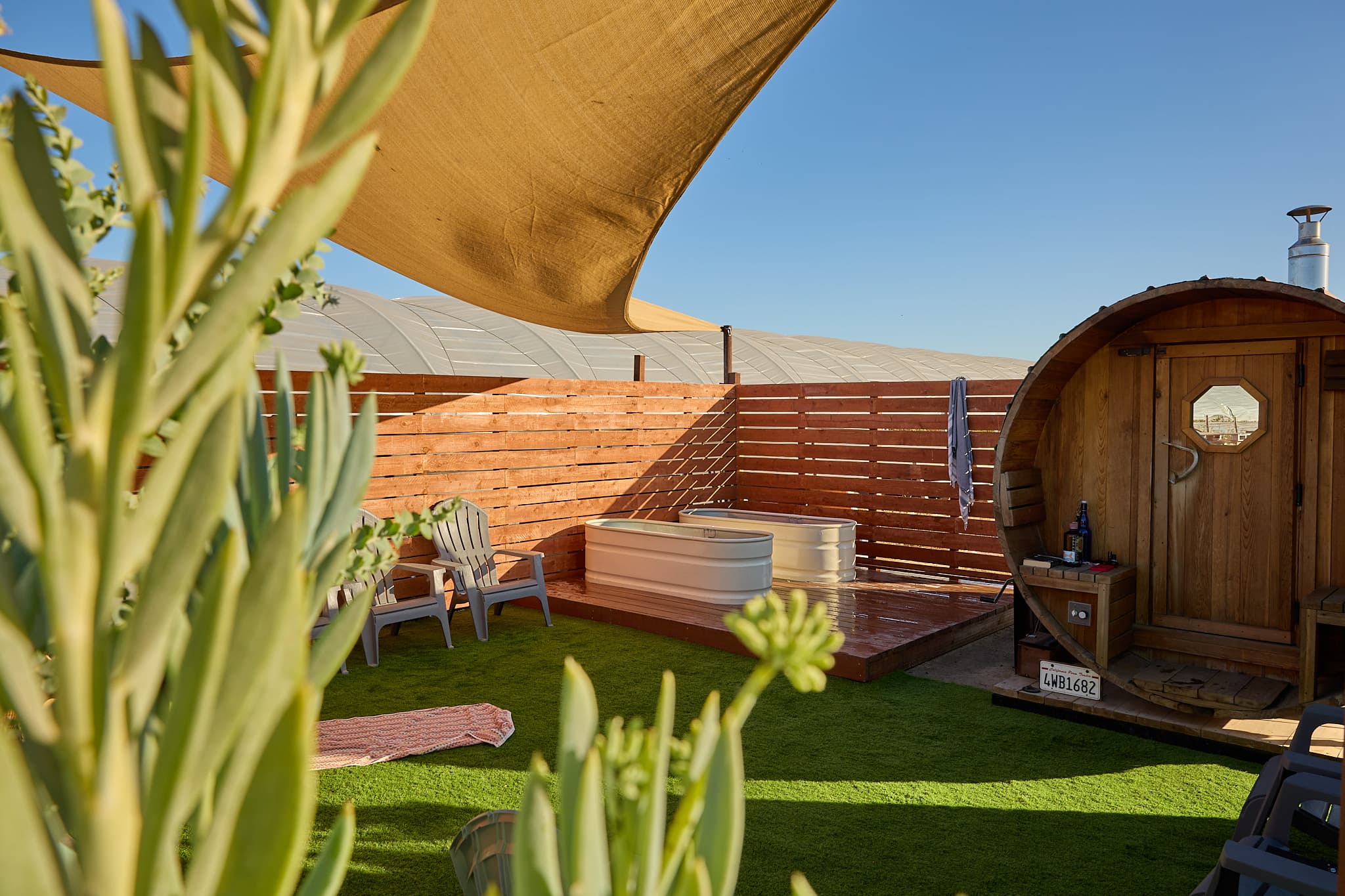 The barrel sauna and cold plunges under a shade sail at SLO Ranch Farms